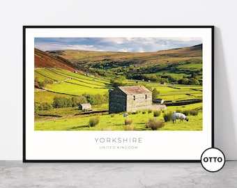 May include: A framed print featuring a scenic landscape of Yorkshire, United Kingdom. The image showcases a stone building in a green field with sheep, rolling hills, and a blue sky. The text "YORKSHIRE UNITED KINGDOM" is displayed at the bottom.