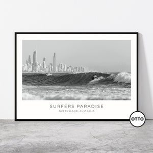 May include: Black and white photograph of a surfer riding a wave in front of the city skyline of Surfers Paradise, Queensland, Australia. The text "SURFERS PARADISE" and "QUEENSLAND, AUSTRALIA" is printed below the image.