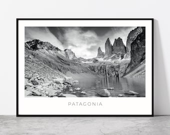 May include: Black and white framed print of the Patagonia mountain range. The image features a lake in the foreground with rocky shores, and towering peaks in the background. The word "PATAGONIA" is printed in a clean font at the bottom of the frame.