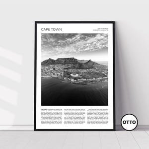 Peut inclure: Tirage encadré en noir et blanc de Cape Town, Afrique du Sud. L'image présente une vue panoramique de la ville, de la Montagne de la Table et de la mer. Le texte "CAPE TOWN" est en haut, avec des coordonnées. L'impression est affichée sur un mur blanc.