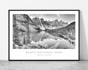 May include: Black and white framed print of Banff National Park in Alberta, Canada. The landscape features a serene lake reflecting the surrounding mountains and evergreen trees. The text "BANFF NATIONAL PARK" and "ALBERTA, CANADA" are printed at the bottom.