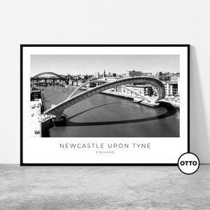 Può includere: Fotografia in bianco e nero del Tyne Bridge a Newcastle upon Tyne, in Inghilterra. Il ponte è una struttura moderna e curva che attraversa il fiume Tyne. La foto è stata scattata dall'alto, guardando verso il basso il ponte e il fiume.