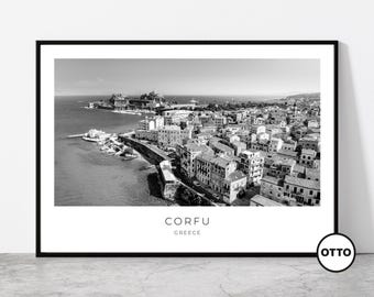 May include: Black and white framed print of Corfu, Greece. The aerial view shows a coastal city with buildings, a fortress, and the sea. The word "CORFU" and "GREECE" are printed in white at the bottom of the print.