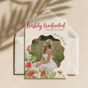 May include: A graduation announcement card with the text "Freshly Graduated CLASS OF 2026" in red script. The card features a photo of a smiling person in a white dress, surrounded by a strawberry and floral design.