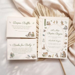 May include: A set of three cream-colored paper cards featuring illustrations of woodland animals reading books. The main invitation reads A New Chapter Begins, while the smaller cards are labeled Diaper Raffle and Books for Baby with text.