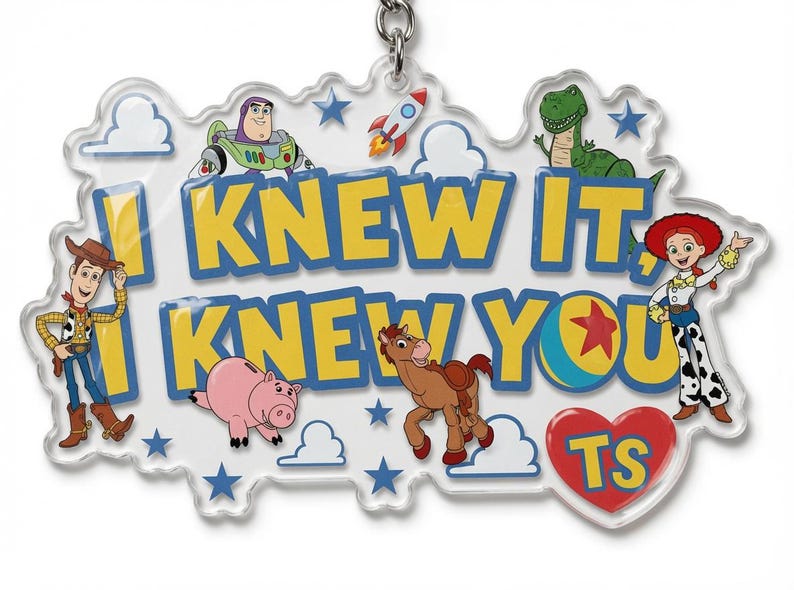 May include: A clear acrylic keyring featuring the text I KNEW IT, I KNEW YOU in yellow with blue outlines. The design includes illustrations of Woody, Buzz Lightyear, Rex, Jessie, Bullseye, and Hamm, along with a rocket, clouds, stars, and a red heart with TS.