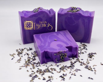 May include: Three bars of purple lavender soap with dried lavender flowers on top. The soap is handmade and has a swirl design. The soap is labeled "Empathy Essentials".