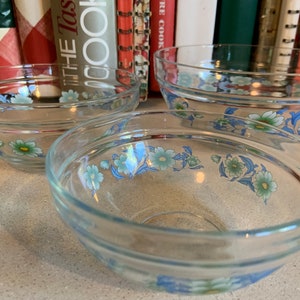 May include: Three clear glass bowls with a floral design. The bowls have a blue and green floral pattern with white accents.
