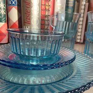 May include: A set of blue glass dishes with a ribbed pattern. The set includes a bowl, a saucer, and a large plate.