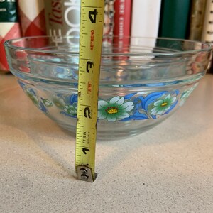 May include: A clear glass mixing bowl with a floral design in blue, white, and green. The bowl is 3 inches tall.