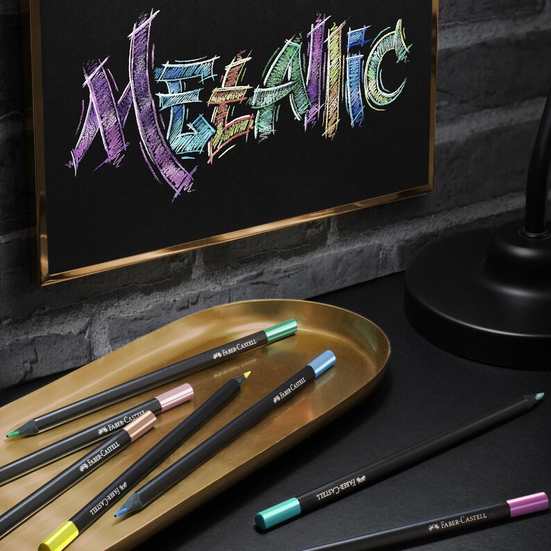 May include: A collection of Faber-Castell metallic colored pencils with black barrels and colored tips, arranged on a gold-toned oval tray. Above the tray, a framed piece of black paper displays the word METALLIC written in vibrant, multi-colored script.