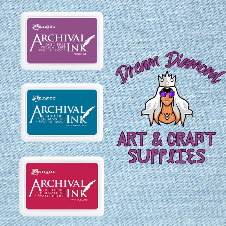 May include: Three ink pads with the text "Ranger Archival Ink" in white on a purple, blue, and red background. The ink pads are labeled with the colors "Aubergine", "Mountain Lake", and "Wine Cellar".