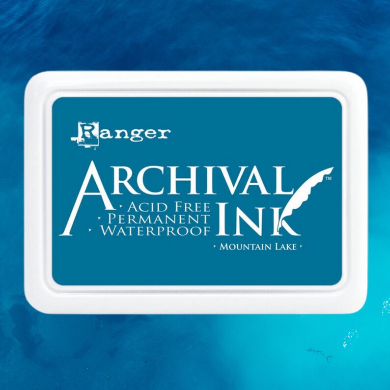 May include: A white ink pad with the words "Ranger Archival Ink" in white lettering on a teal blue background. The ink pad is acid free, permanent, and waterproof. The ink pad is labeled "Mountain Lake".