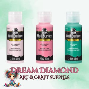 Op de afbeelding: Drie 59 ml flessen FolkArt Multi-Surface Satin acrylverf. De flessen zijn gelabeld met de kleuren: Roze Kwarts, Framboosroos en Lagoon.