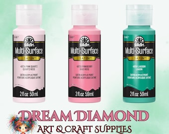 May include: Three 2-ounce bottles of FolkArt Multi-Surface Satin acrylic paint. The bottles are labeled with the color names: Pink Quartz, Pinkberry Baie Rose, and Lagoon.