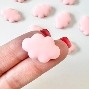 Op de afbeelding: Tien kleine roze wolkvormige bedels. De bedels zijn gemaakt van een glad, glanzend materiaal en zijn perfect om een vleugje whimsy toe te voegen aan elk knutselproject.
