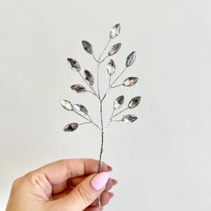 May include: Silver wire branch with clear crystal leaves. The branch is approximately 15 cm long and features a delicate, elegant design.