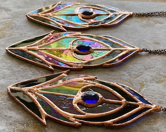 May include: Three iridescent stained glass peacock feather ornaments with copper wire accents and blue glass eyes. Each ornament has a chain attached for hanging.