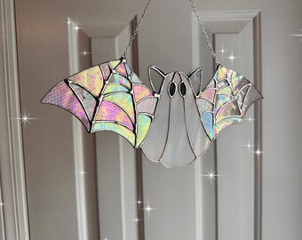 May include: A stained glass bat with iridescent wings and a web design. The bat is hanging from a silver chain.