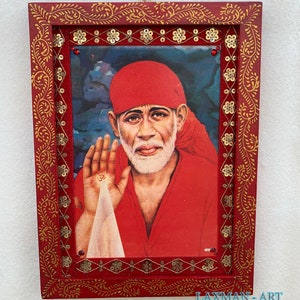 Puede incluir: Una imagen enmarcada de una figura religiosa con un turbante rojo y una túnica roja. El marco es rojo con detalles dorados y tiene un borde decorativo de lentejuelas doradas.