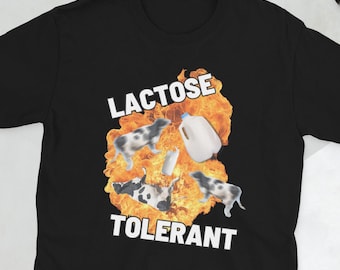 May include: Black t-shirt with a graphic design featuring the words "LACTOSE TOLERANT" in white block letters. The design includes cartoon cows, milk bottles, and a milk jug set against a fiery background.