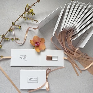 May include: A set of white boxes with a rose gold ribbon tied around each one. The boxes are arranged in a fan shape and contain USB drives with a rose gold and clear design. The boxes are labeled with the text "Thank You" and "Memories to Treasure".