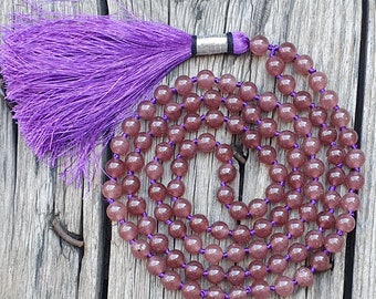 May include: A purple and brown mala necklace with a purple tassel. The necklace is made of round beads and is strung on a thin cord.