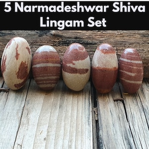 May include: Set of five brown and white striped Narmadeshwar Shiva Lingam stones. The stones are smooth and oval-shaped.
