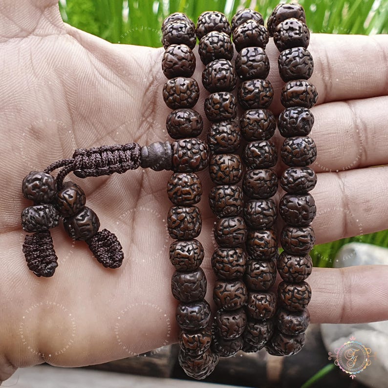 May include: A brown wooden mala prayer bead necklace with a tassel. The beads are round and have a textured surface.