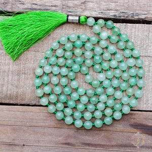 May include: A green jade mala bead necklace with a green tassel. The beads are round and smooth, and the tassel is made of a soft, silky material.