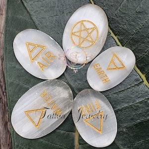 May include: Five white selenite stones with gold symbols and the words "Air", "Earth", "Fire", "Water", and a pentagram.