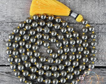 May include: A long strand of round, metallic gray beads arranged in a circular coil. The beads are strung on a bright yellow cord that extends from the center to form a large, vibrant yellow tassel with a silver-toned metal cap at the top.