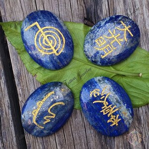May include: Four blue lapis lazuli stones with gold painted symbols. The symbols are the five elements of earth, water, fire, air, and ether.