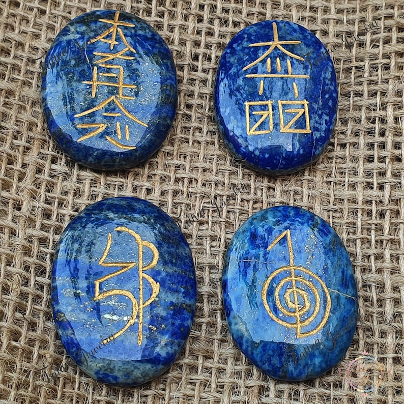May include: Four smooth, oval-shaped lapis lazuli stones with gold symbols etched on them. The symbols are "Jin", "Kyo", "Rei", and "Sei".