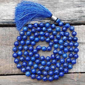 以下が含まれることがあります： 青いラピスラズリのマラービーズネックレスに青いタッセルが付いています。ネックレスは108個のビーズでできており、長さは約46cmです。