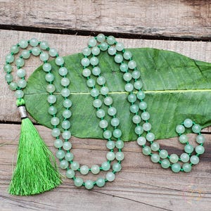 May include: A green jade mala bead necklace with a green tassel. The necklace is made of 108 beads and is approximately 46 cm long.
