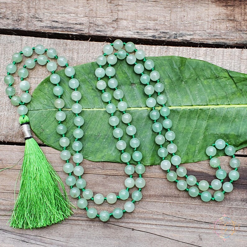 May include: A green jade mala bead necklace with a green tassel. The necklace is made of 108 beads and is approximately 46 cm long.
