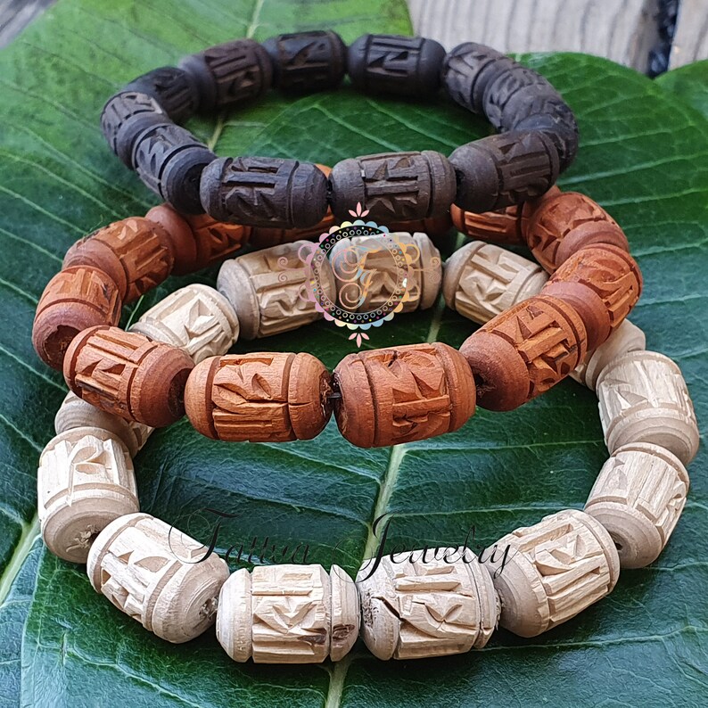 Pode incluir: Tr&ecirc;s pulseiras de madeira com entalhes intrincados. A pulseira superior &eacute; marrom escura, a pulseira do meio &eacute; marrom clara e a pulseira inferior &eacute; branca.