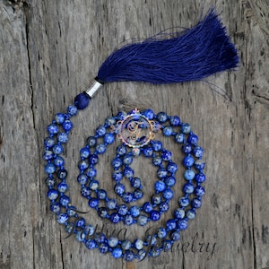 May include: A blue lapis lazuli mala necklace with a tassel. The necklace is made of 108 beads and is approximately 18 inches long. The tassel is made of blue silk.