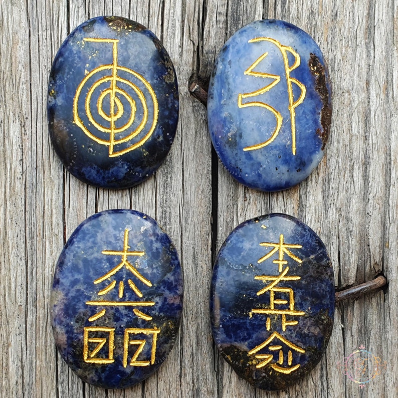 Puede incluir: Cuatro piedras lisas de forma ovalada de color azul con s&iacute;mbolos dorados grabados en ellas. Los s&iacute;mbolos son: "Om", "Shanti", "Tai Chi" y "Zen".
