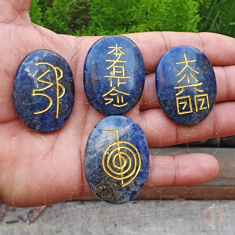 May include: Five oval-shaped blue lapis lazuli stones with gold symbols and characters. The stones are smooth and polished. The symbols include the five elements of Chinese philosophy: wood, fire, earth, metal, and water.