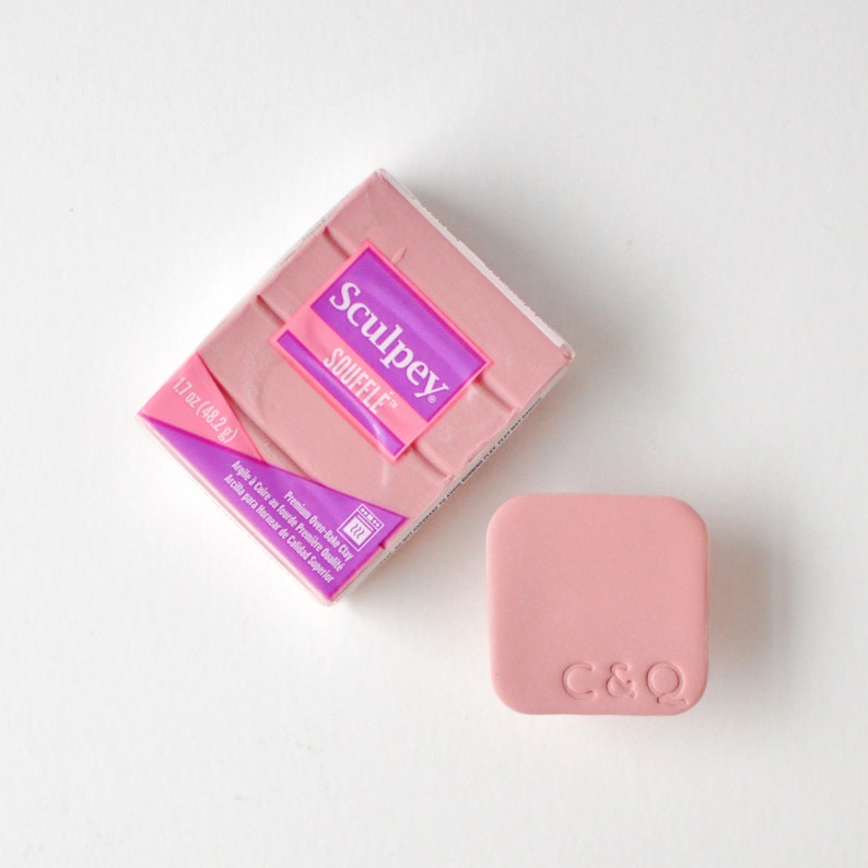 May include: A pink block of Sculpey Souffle brand oven-bake clay with the text "Sculpey Souffle" and "Premium Oven-Bake Clay" on the packaging. The clay is 1.7 oz (48.2 g).