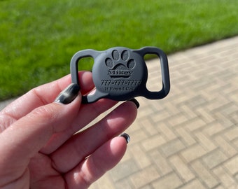 May include: Black silicone dog tag with a paw print and the text "Mikey 777-777-7777 If Found Call".