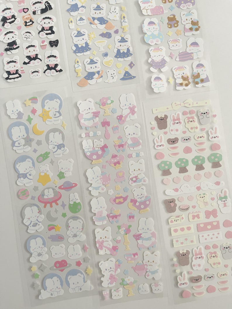 May include: A set of six sheets of stickers featuring cute cartoon bunnies in various poses and outfits. The stickers are on a clear background and are perfect for adding a touch of whimsy to planners, journals, and other craft projects.