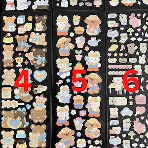 May include: Three sheets of stickers featuring cute cartoon bears in various poses and settings. The stickers are on a black background and include images of bears wearing hats, holding flowers, and sitting on cakes. The stickers are labeled with the numbers 4, 5, and 6.