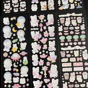 May include: A sheet of colorful stickers featuring cute cartoon bunnies in various poses and settings. The stickers include bunnies in space, bunnies having tea parties, and bunnies with hearts and flowers.