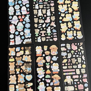 May include: Six sheets of colorful stickers featuring cute cartoon bears, bunnies, and chicks. The stickers are on a black background and are perfect for decorating planners, journals, and other items.