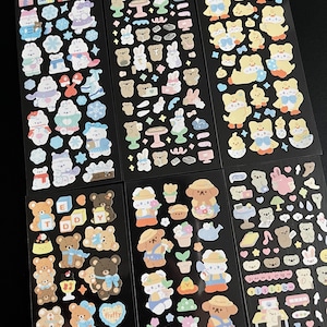 May include: Six sheets of colorful stickers featuring various cute cartoon animals, including bears, bunnies, and ducks. The stickers are on black backgrounds and feature different themes, such as winter, spring, and summer.