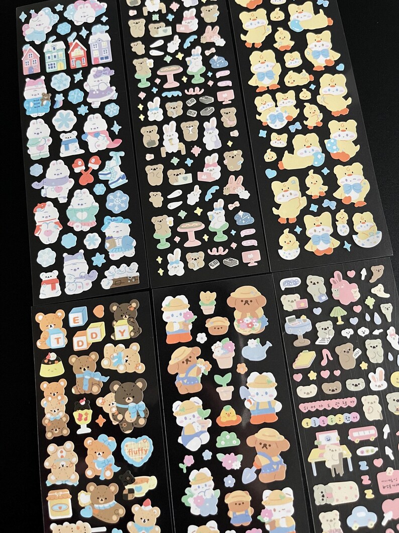 May include: Six sheets of colorful stickers featuring various cute cartoon animals, including bears, bunnies, and ducks. The stickers are on black backgrounds and feature different themes, such as winter, spring, and summer.