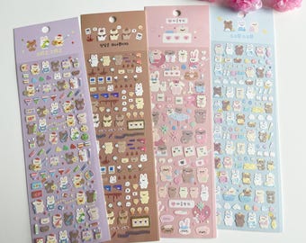 May include: Four sheets of colourful stickers featuring cute cartoon animals, including bears, rabbits, and birds. The stickers are arranged in a grid pattern and are perfect for adding a touch of whimsy to journals, planners, and other craft projects.